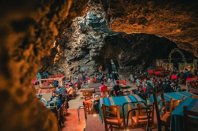 Un restaurante en cueva con mesas bajo el techo de roca